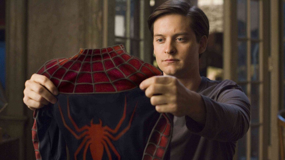 Tobey Maguire's Peter Parker holds up his suit to look at it