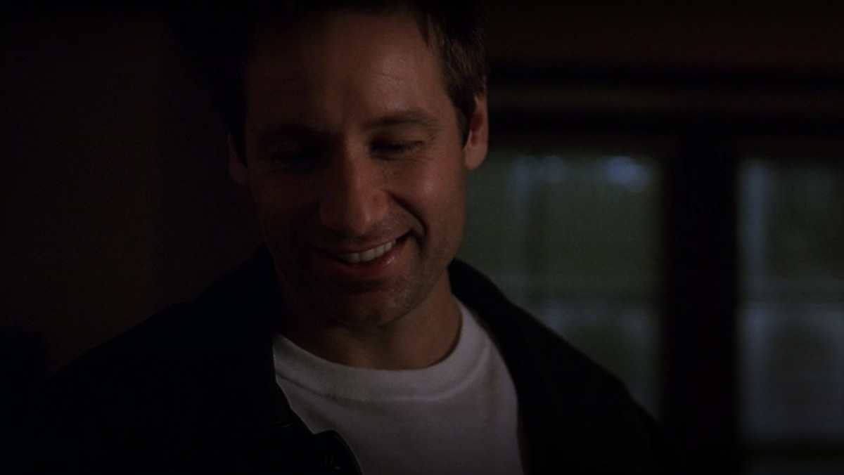 Mulder smiles at Scully's present in a scene from The X-Files' "How the Ghosts Stole Christmas."