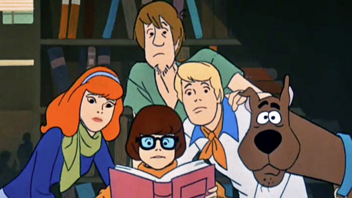 The Scooby Doo Where Are You gang all looks at a book, except Scooby who looks at the screen