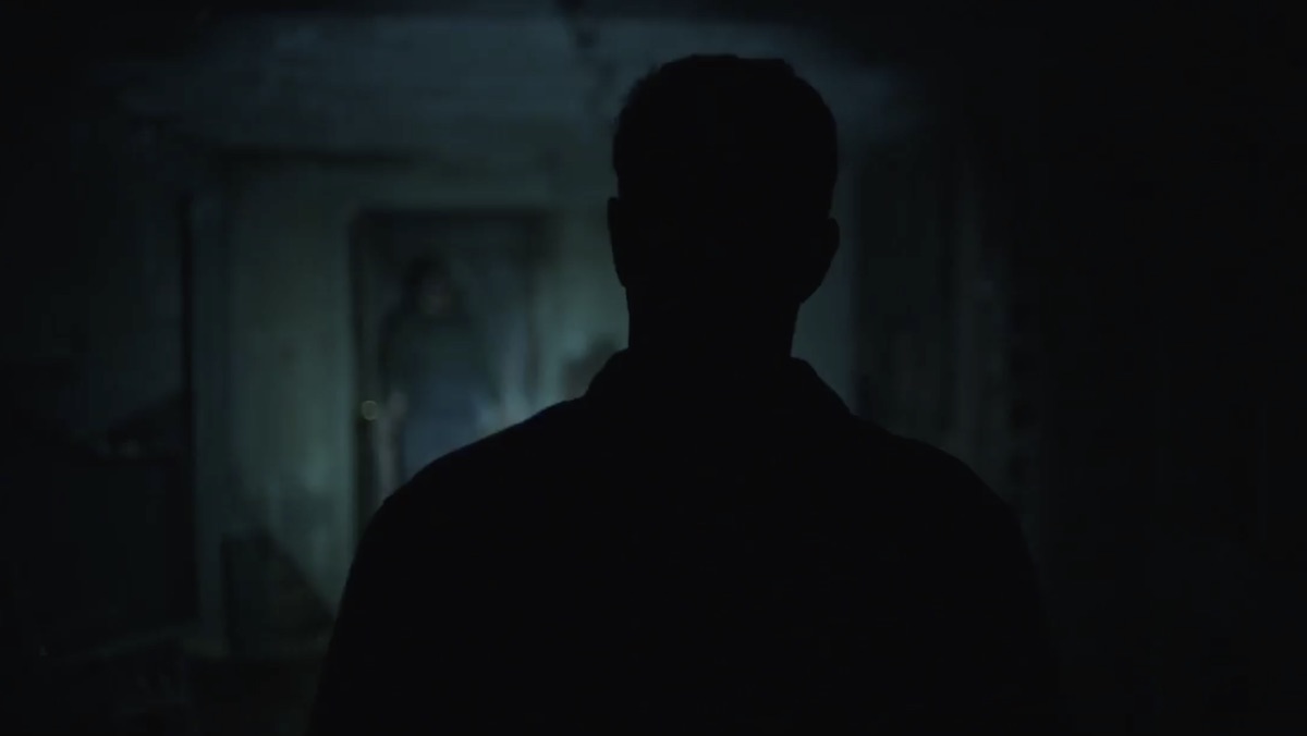 A shadowy figure stands in the doorway