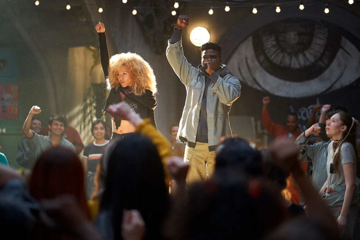 A woman and a man rally a crowd on stage.