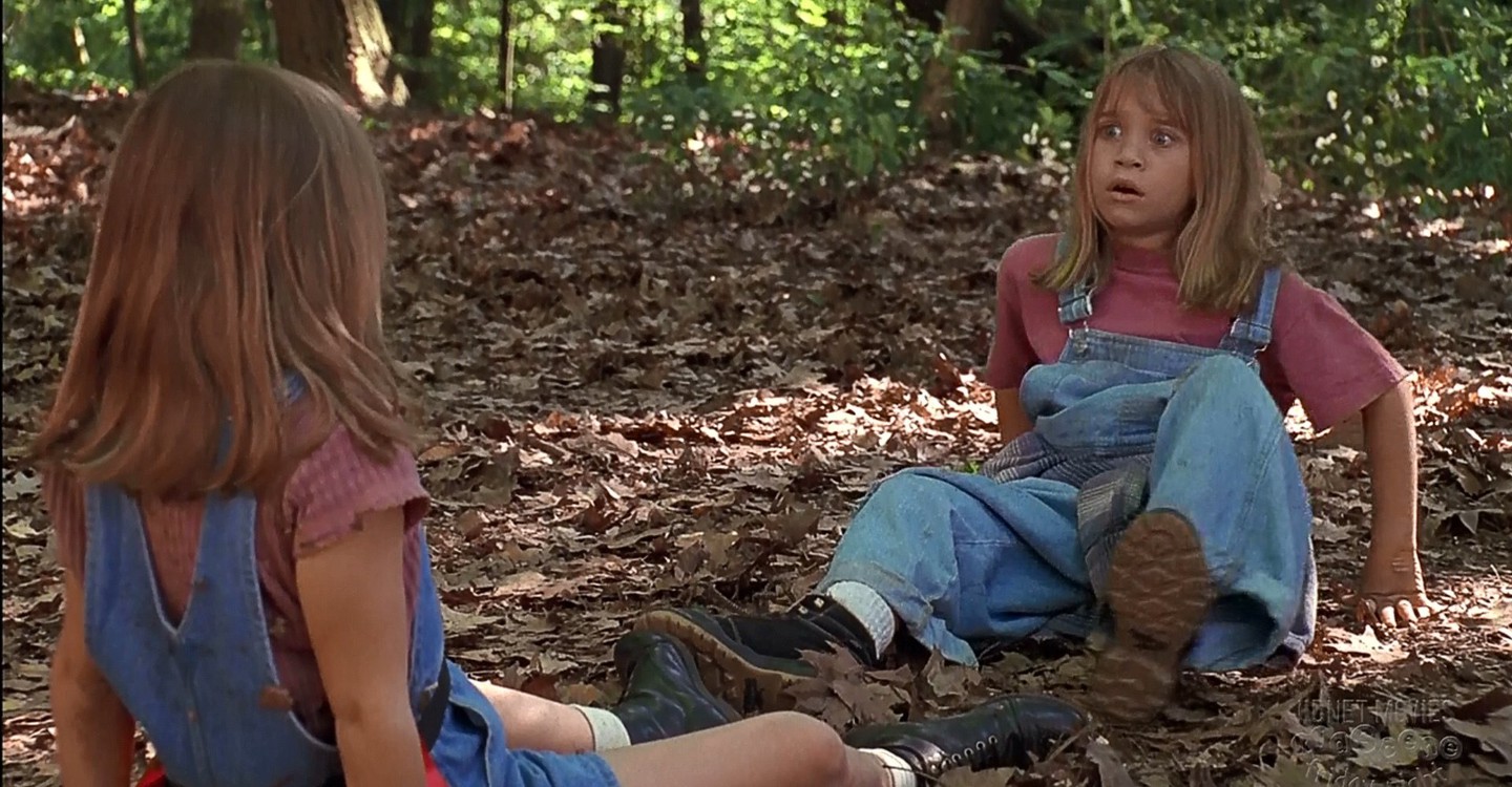 Twin girls stare at each other in woods