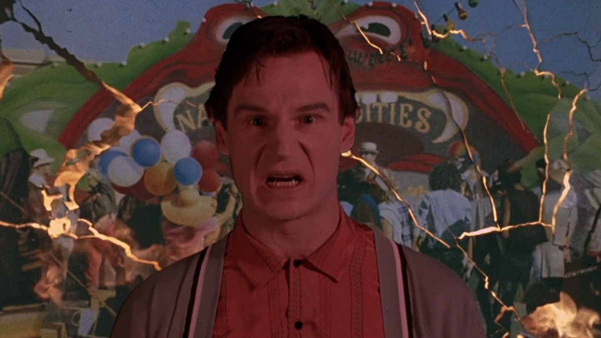 A man stands in front of a carnival game.