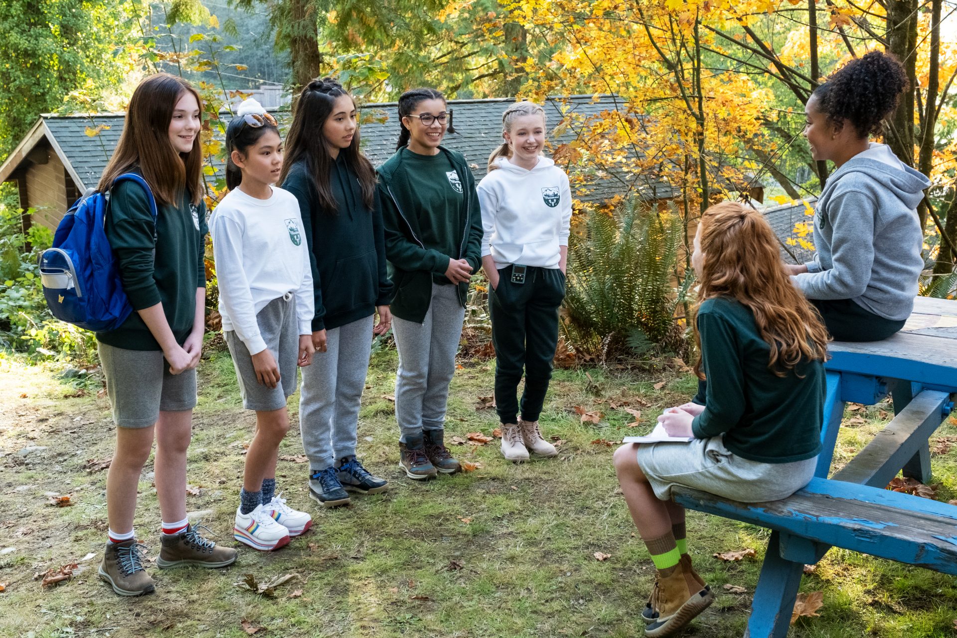 A group of preteen girls stand in a line facing two other girls 