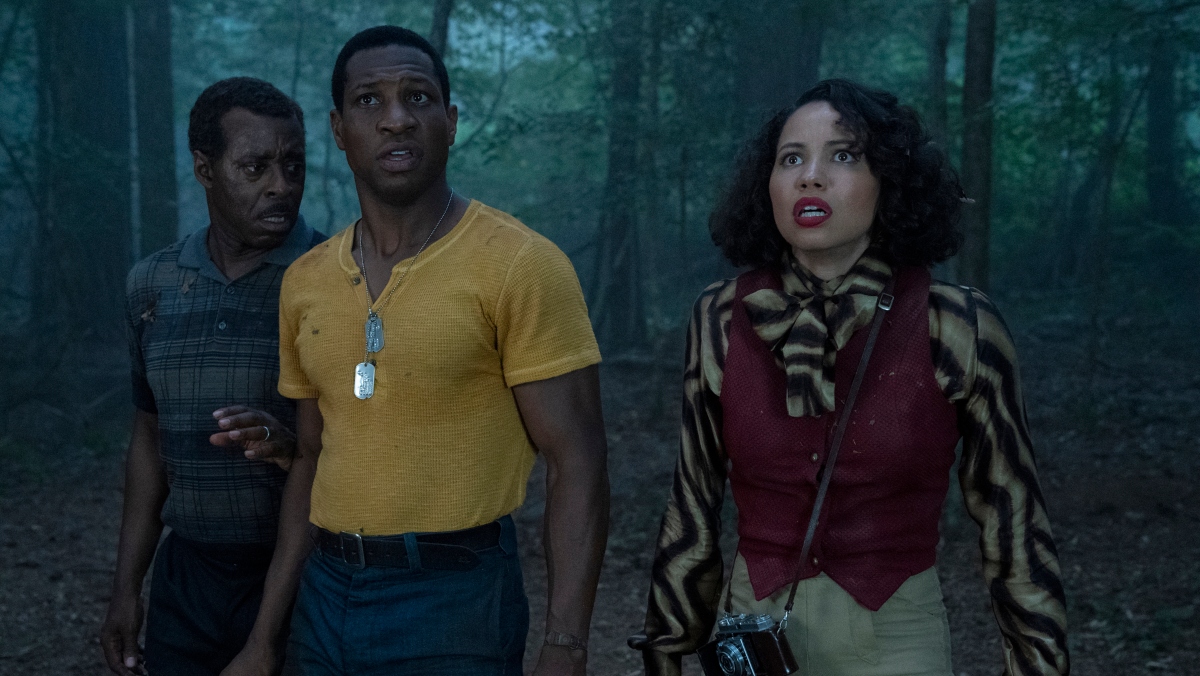 A man and two women stand in a dark forest