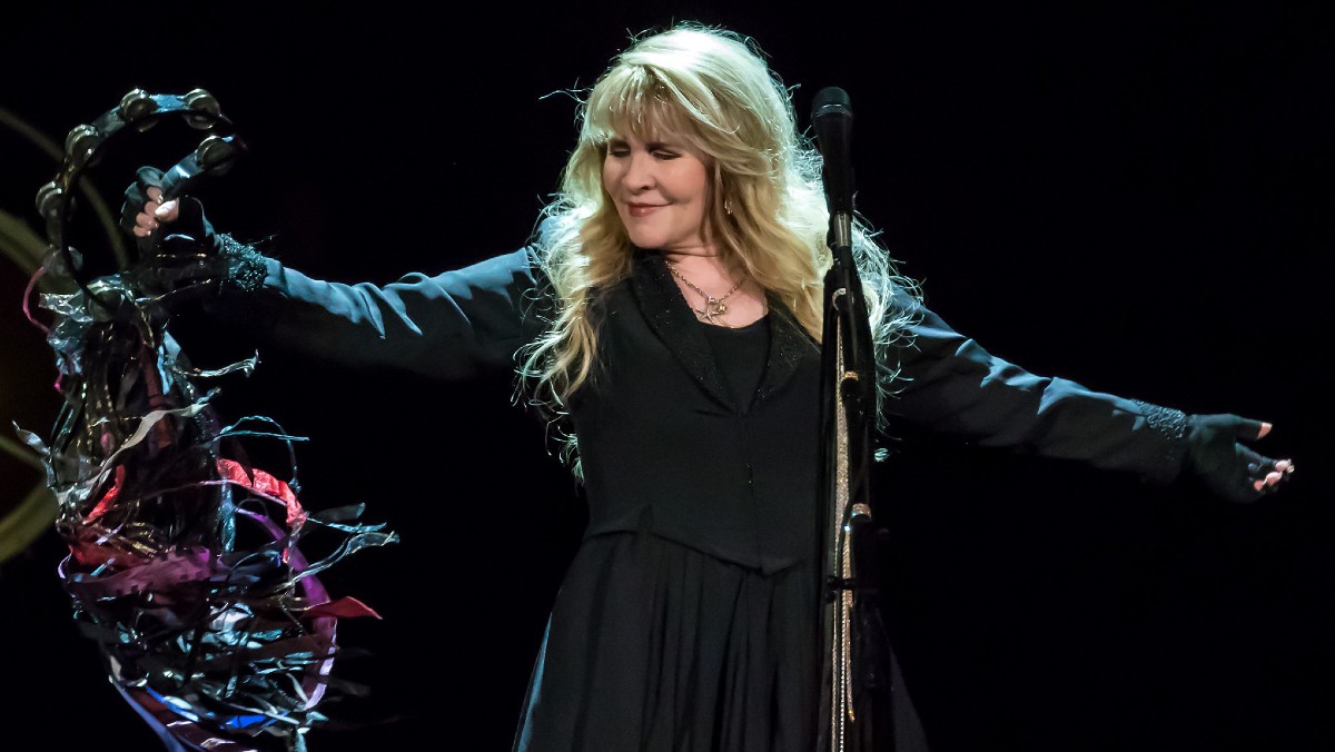 Stevie Nicks performs while dancing with a tamborine.