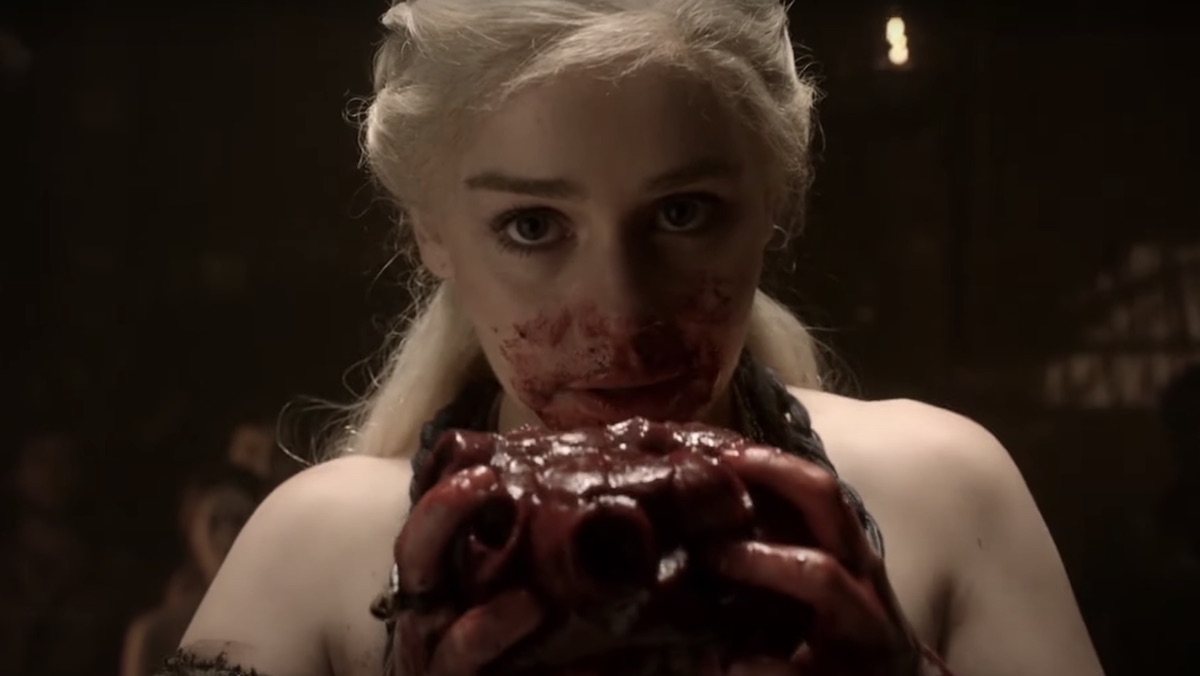 Daenerys Targaryen's face is covered in blood as she holds the horse heart she is eating on Game of Thrones