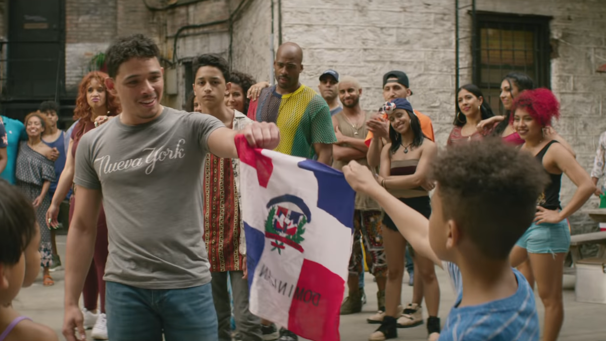 Usnavi and a young boy hold the Dominican Republic flag together.