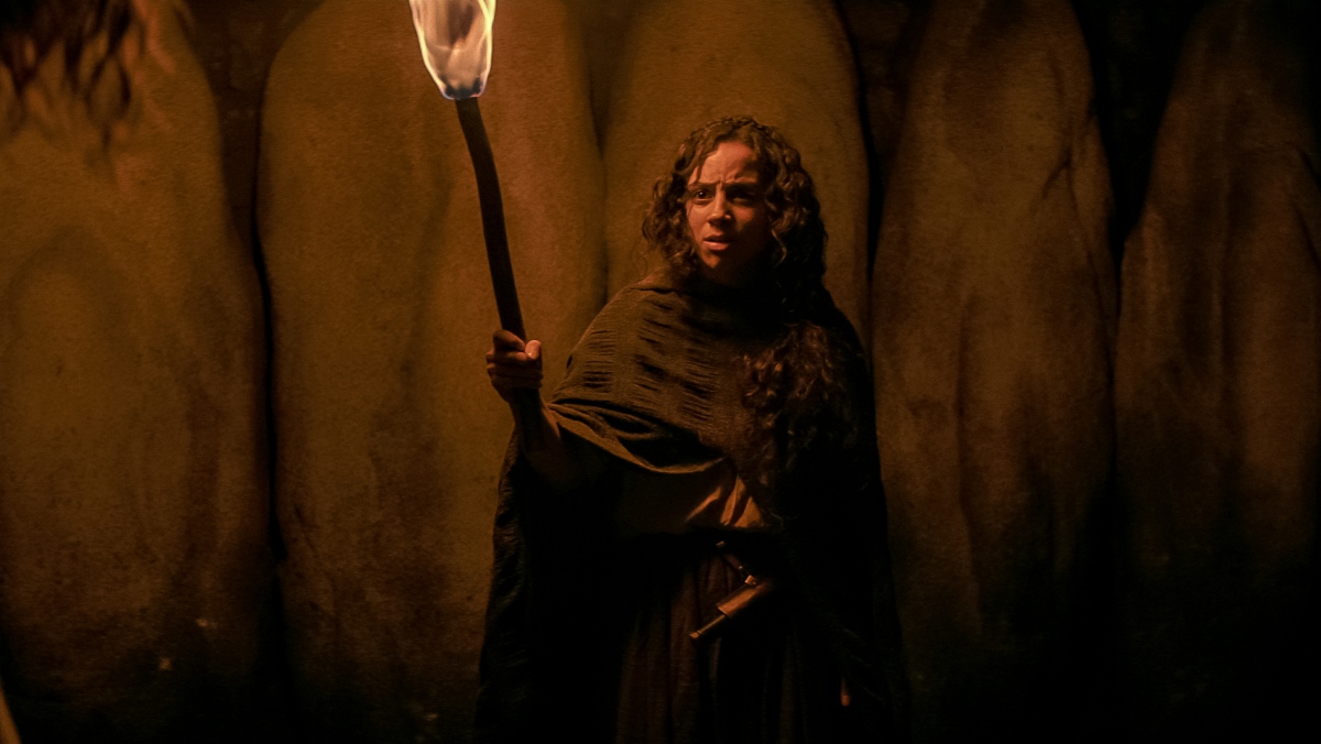 Kiana Maideria as Sarah Fier in Fear Street Part 3 wearing a cloak and carrying a torch