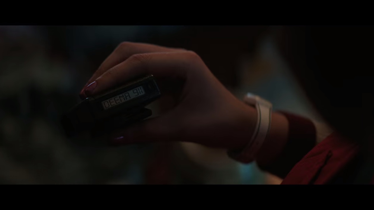 a girl's hand holds up a beeper that says Deena 911