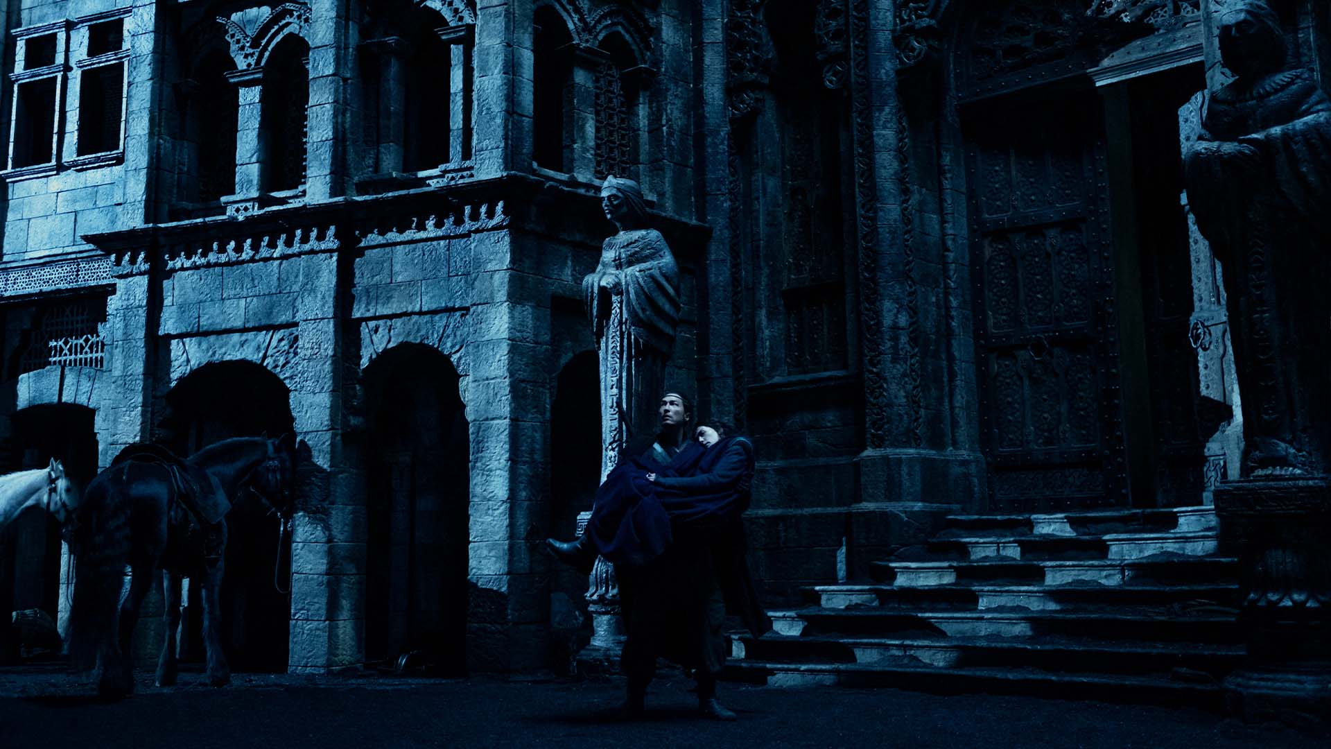 Lan carries Moiraine in front of a shadowy structure