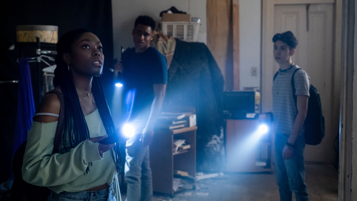 A Black girl and two boys stand in a room with flashlights in Blumhouse film Black as Night