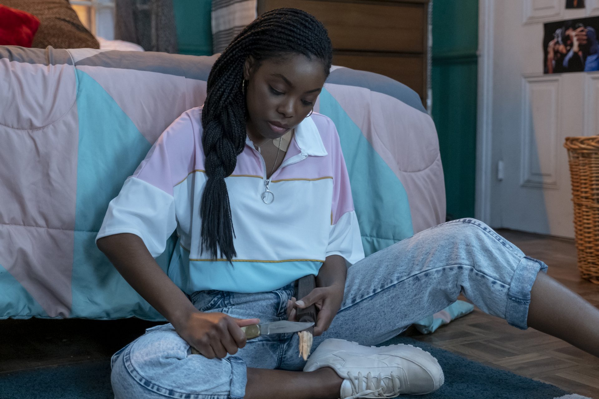 A still from Black as Night shows a young Black girl carving a stake in her bedroom