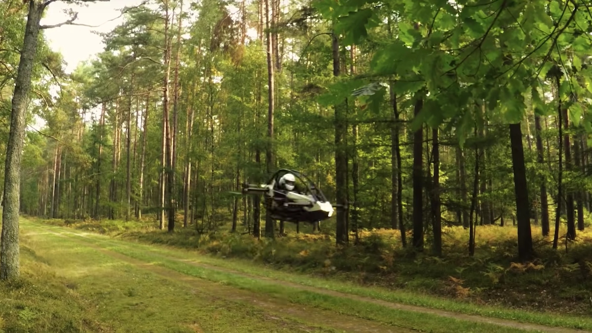 A Jetson One all-electric personal aircraft, which is kind of like an IRL Star Wars speeder bike, makes its way through the forest.