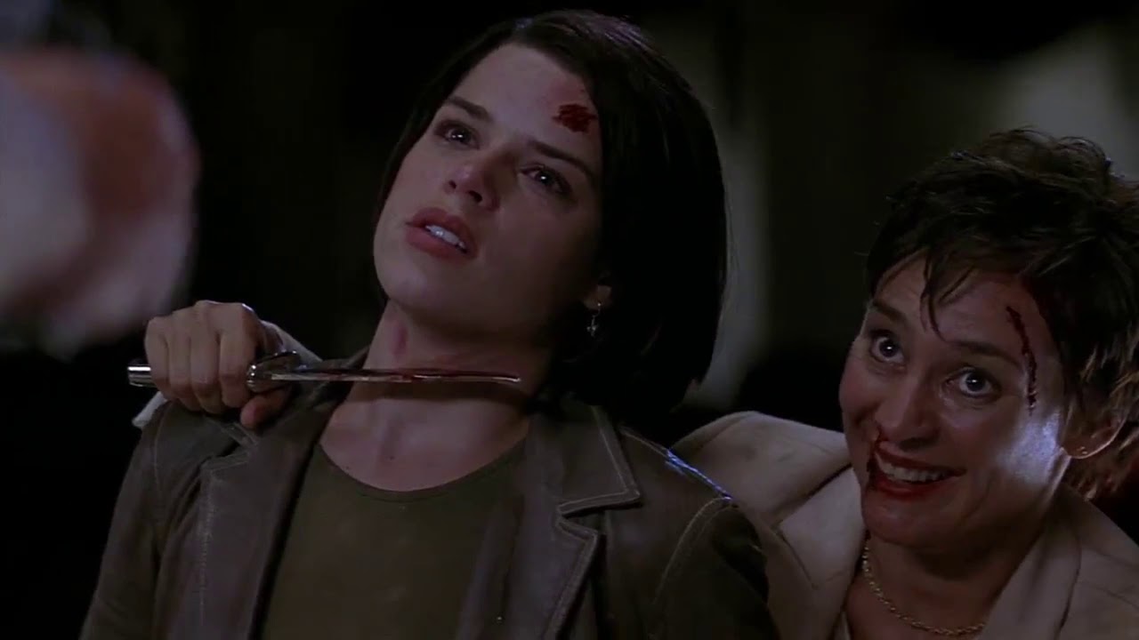 A still from Scream 2 shows Billy Loomis' mother with a knife held to sidney prescotts neck