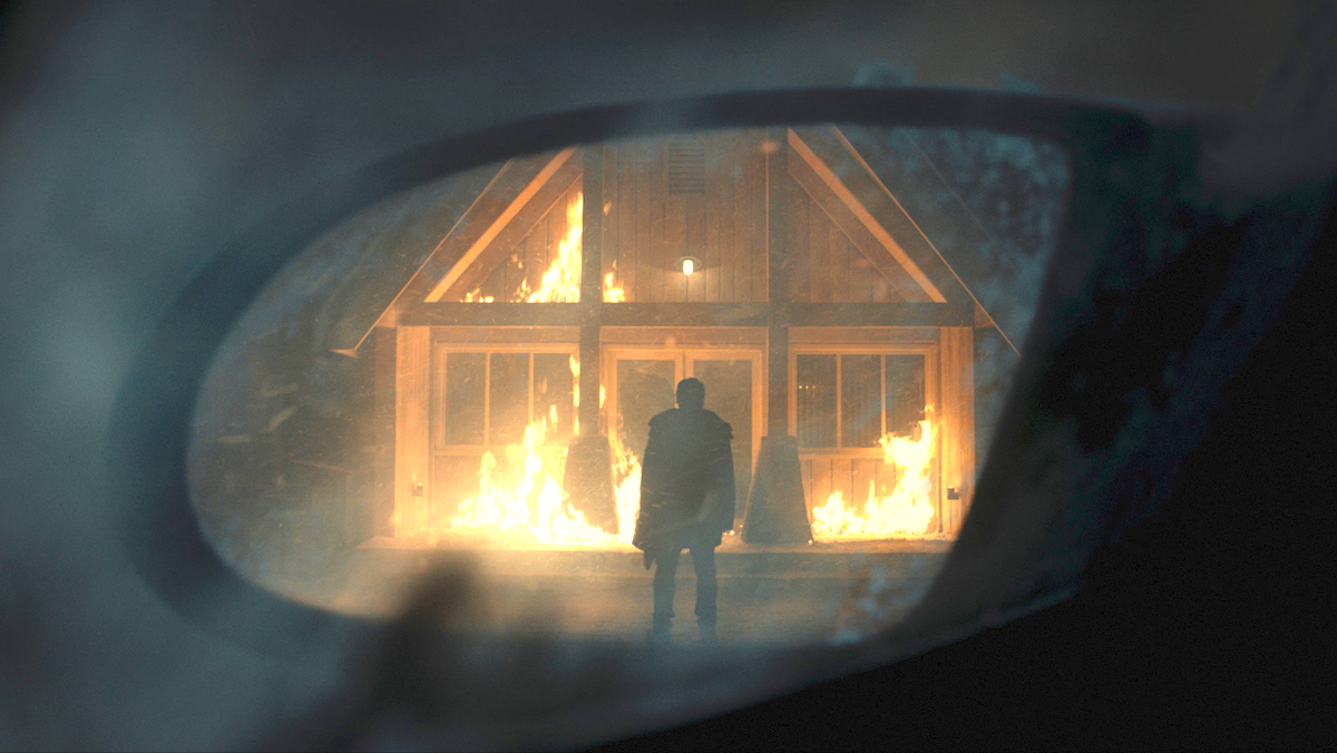 A shaded figure stands in front of a burning lodge in No Exit