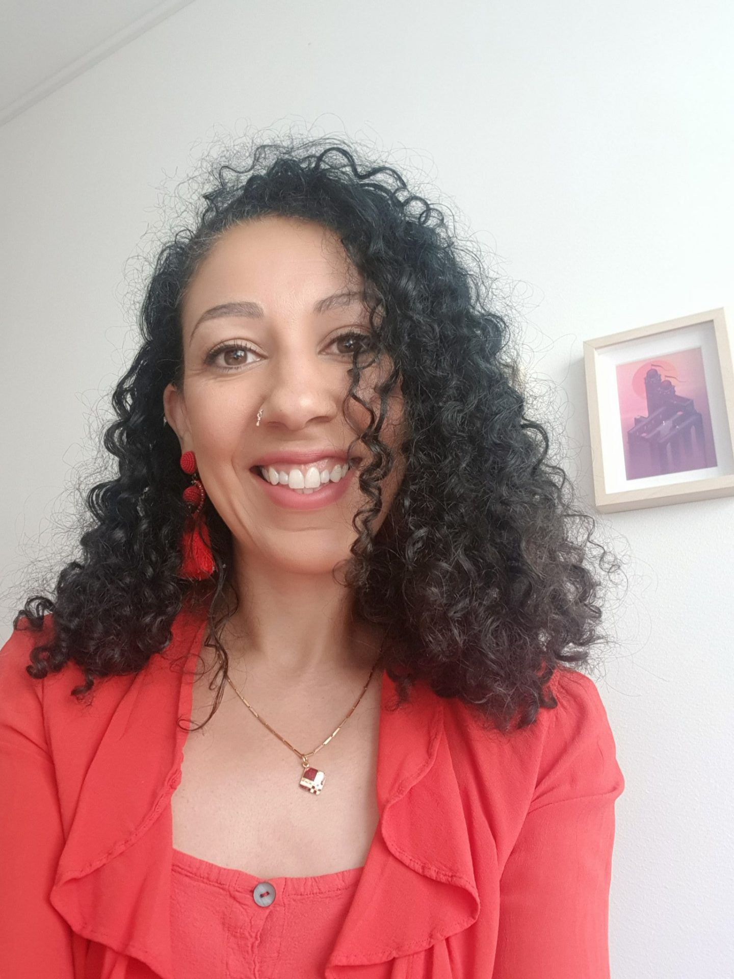 photo of Chella Ramanan wearing red top and smiling with curly hair