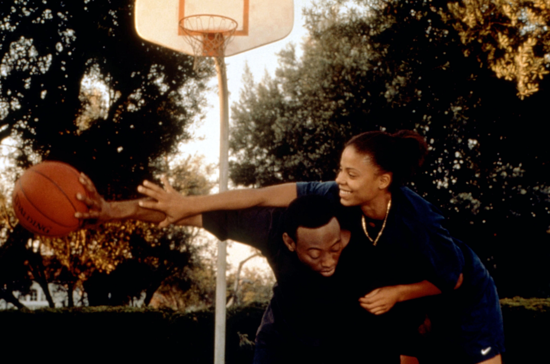 A still from Love and Basketball shows Sanaa Lathan and Omar Epps playing around on a basketball court in Gina Prince-Bythewood's Love and Basketball