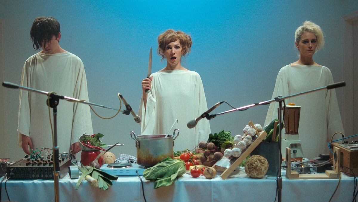 Asa Butterfield, Fatma Mohamed, and Ariane Labed swear smocks and begin their odd "sonic catering" art performance in Flux Gourmet.