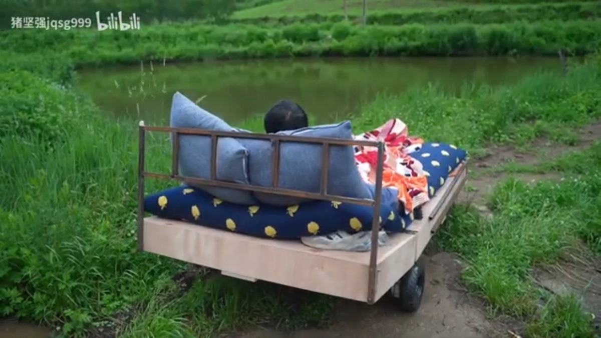 A man in a bed alongside a river