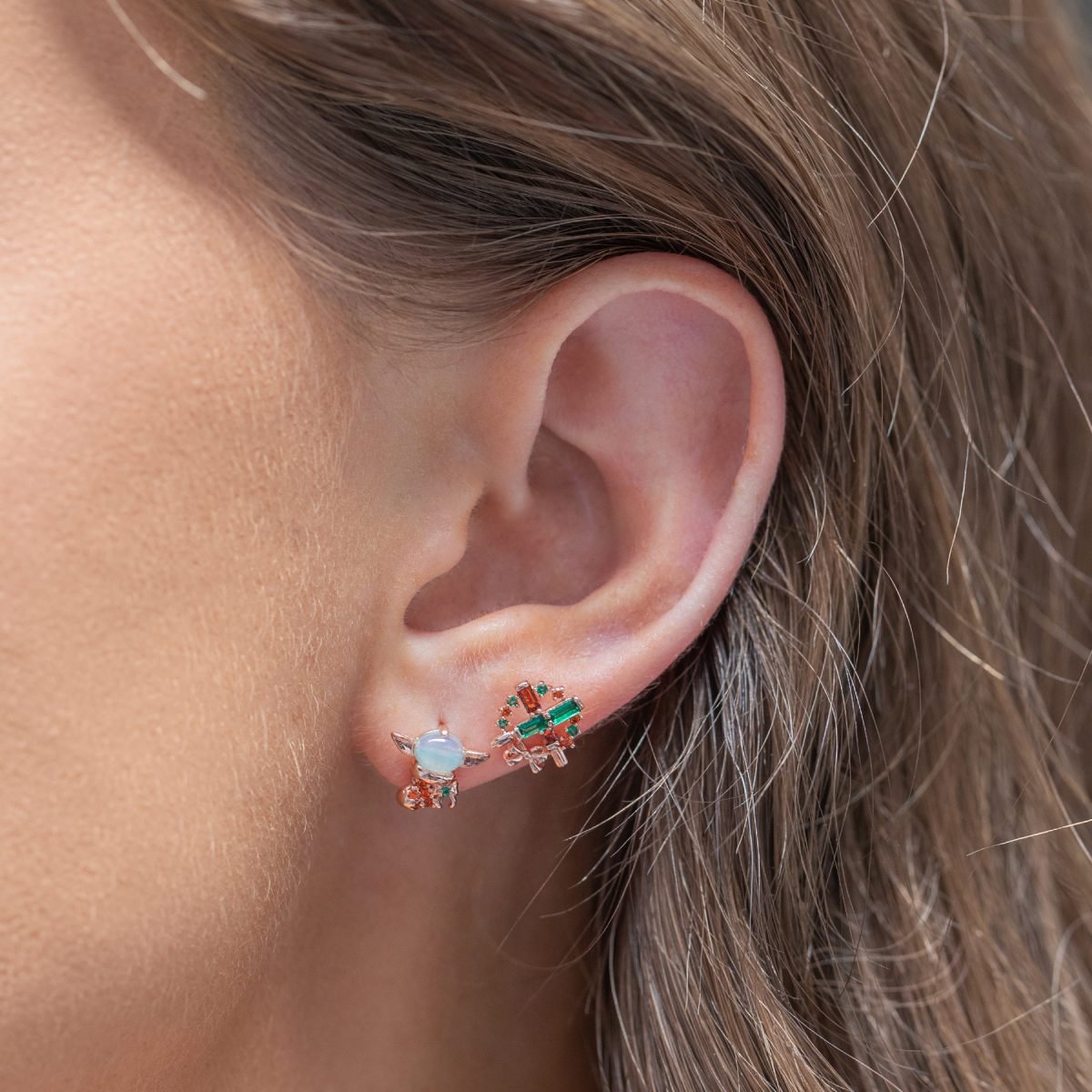 An image of the Grogu and lightsaber holiday earrings on a model