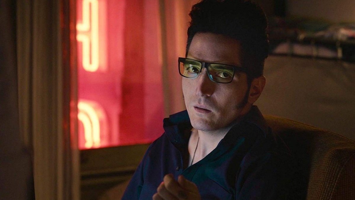 David Dastmalchian as Kurt wearing his glasses and sitting in front of a pink neon sign in Ant-Man