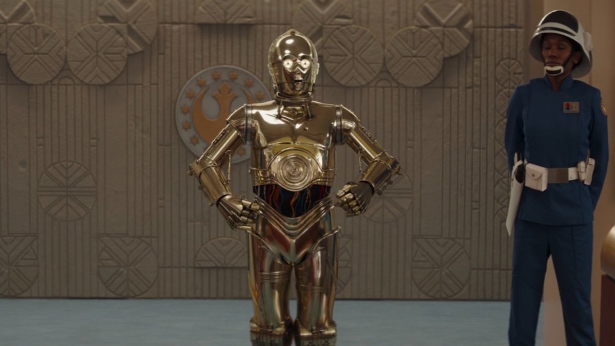 C-3PO flanked by a New Republic guard enters a courtroom on Ahsoka