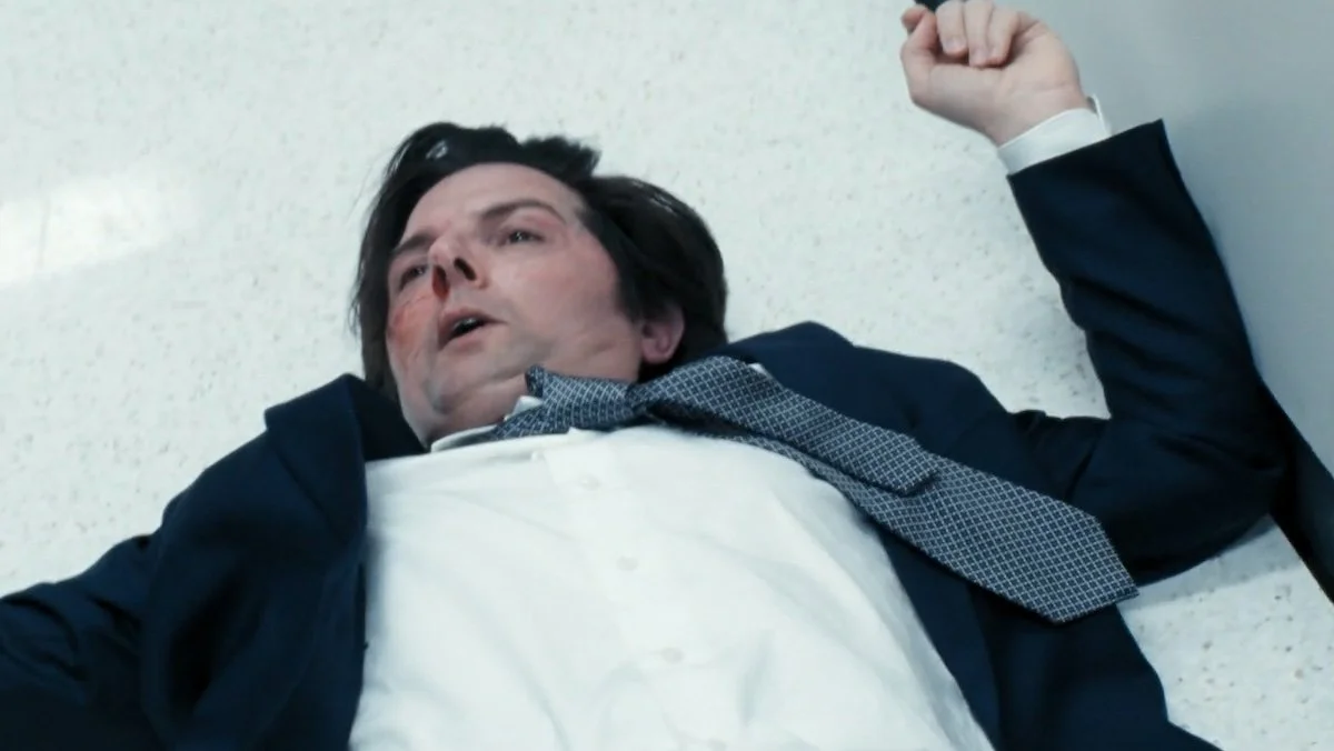 A bloodied Adam Scott on Severance lying down on the floor wounded