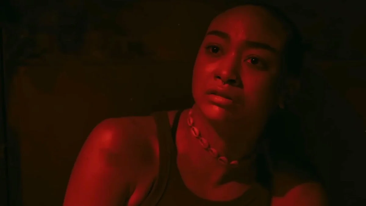 A seated Nora bathed in red light on The Last of Us