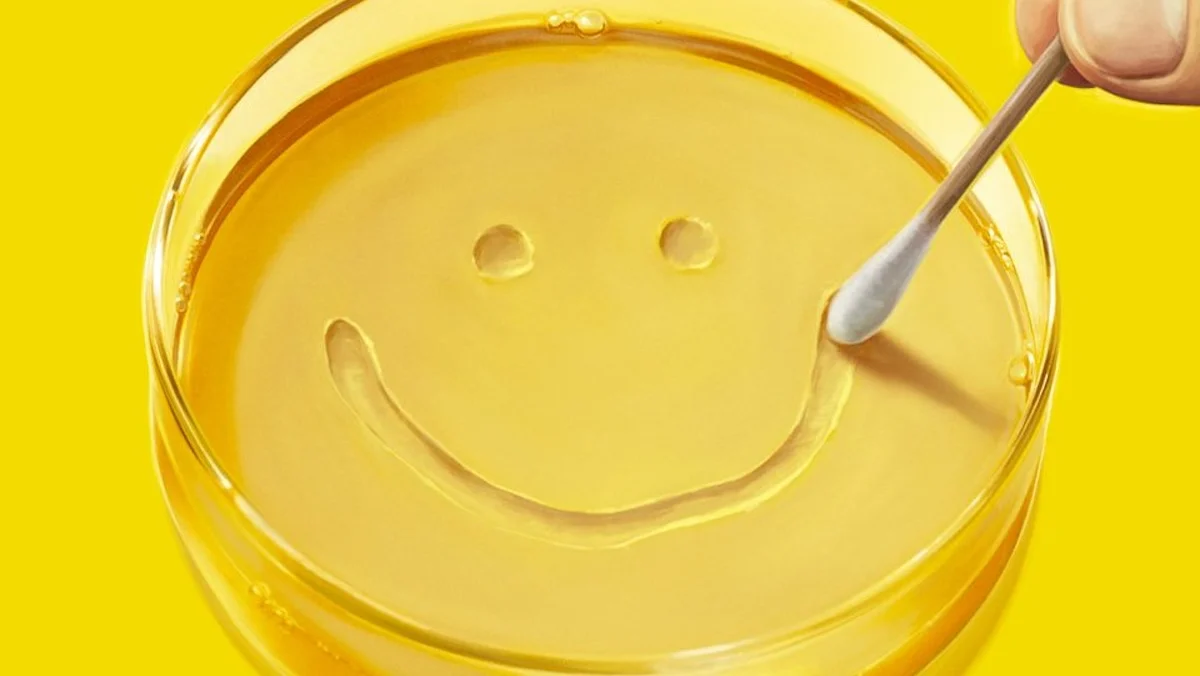A yellow petri dish with a smile made by a cotton swab