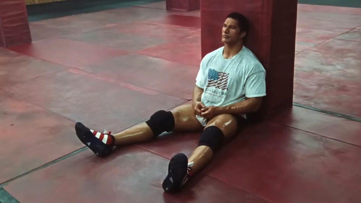 Dwayne Johnson as MMA fighter Mark Kerr sitting glum on the floor of a gym in his workout clothes